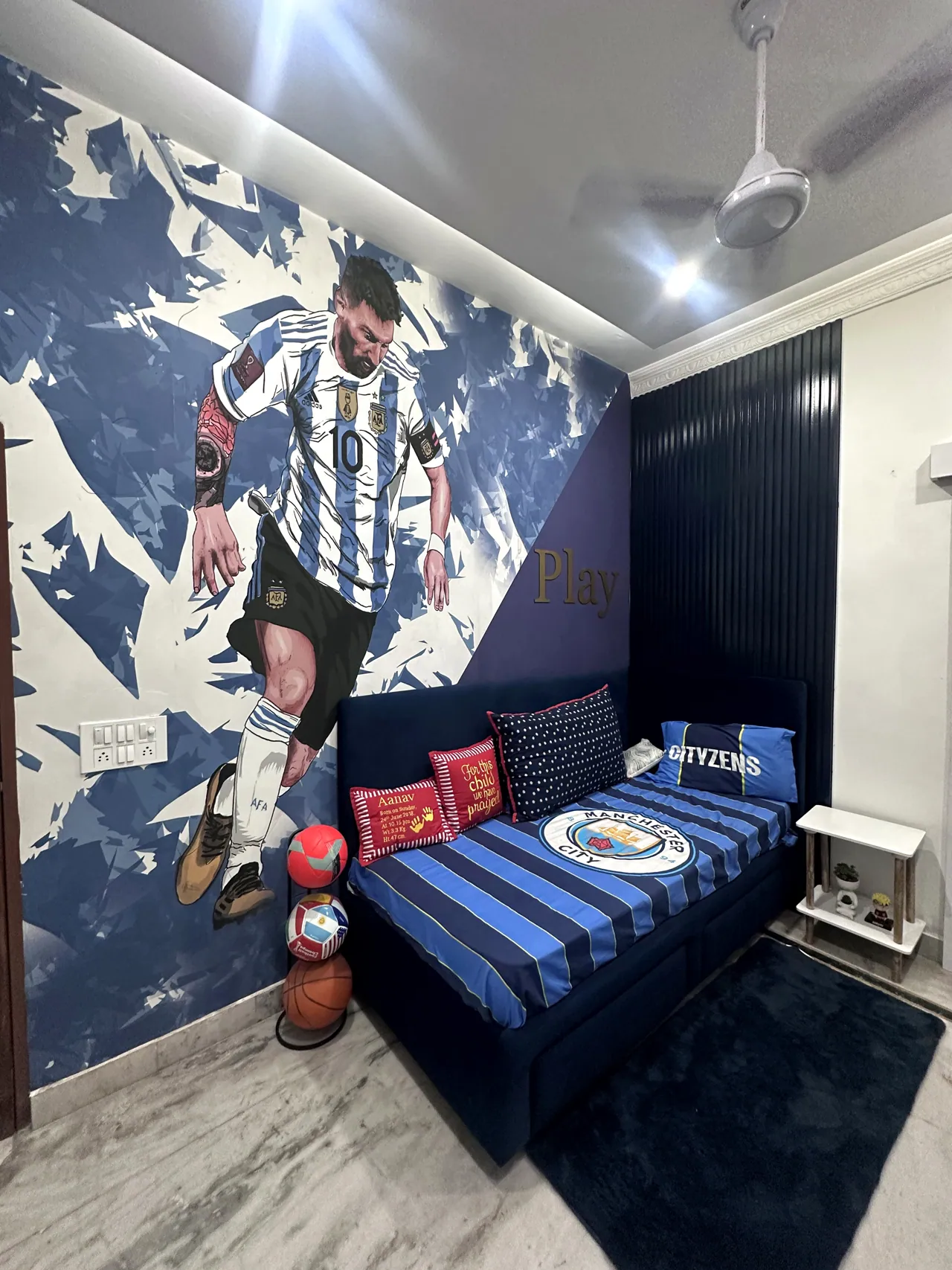 Football-themed children’s bedroom with a blue striped bed, football mural and coordinated storage, designed by DMS Studio