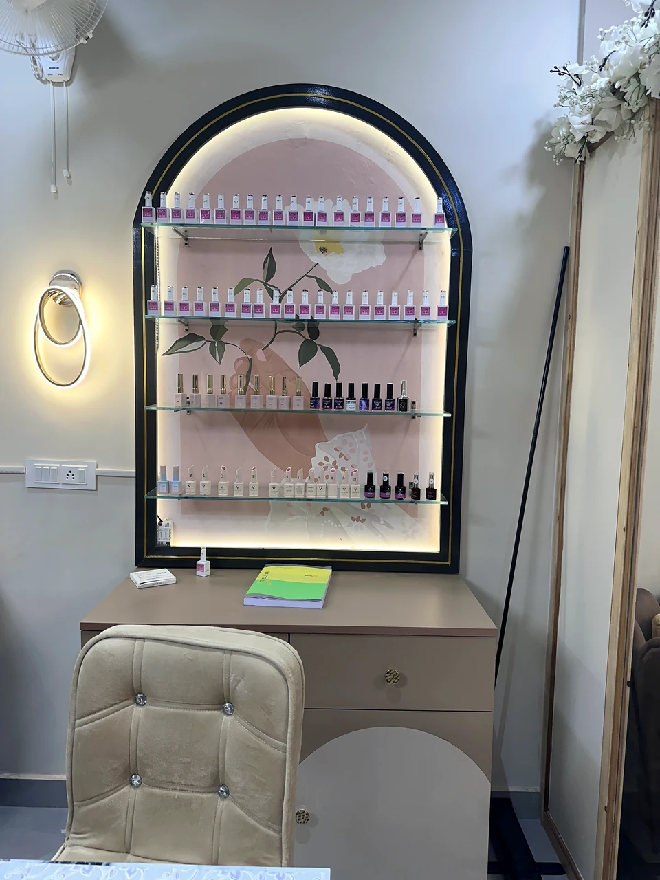 Arched illuminated shelf displaying nail polish colours