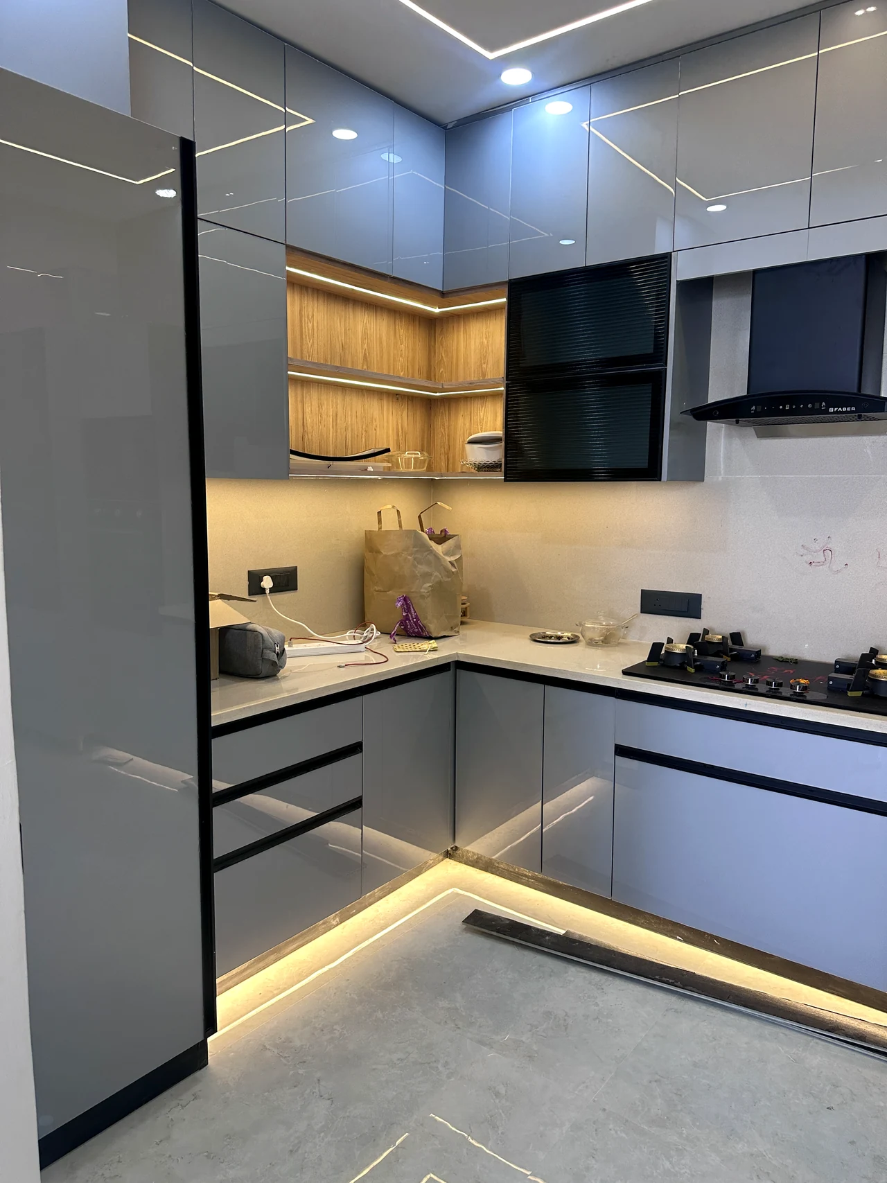 L-shaped modular kitchen with grey cabinetry, black appliances and warm task lighting