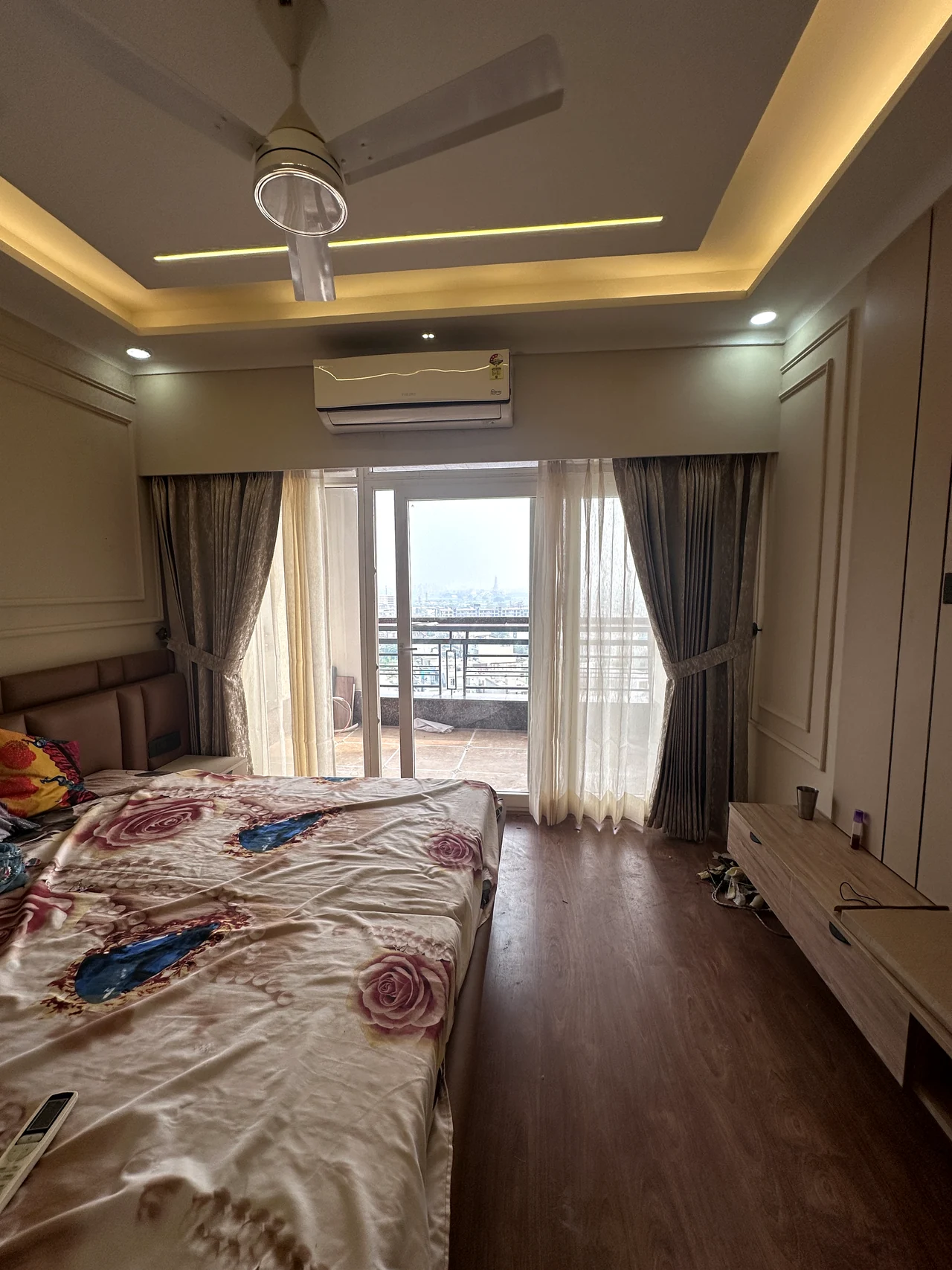 Bedroom with warm wood flooring, soft curtains and balcony daylight