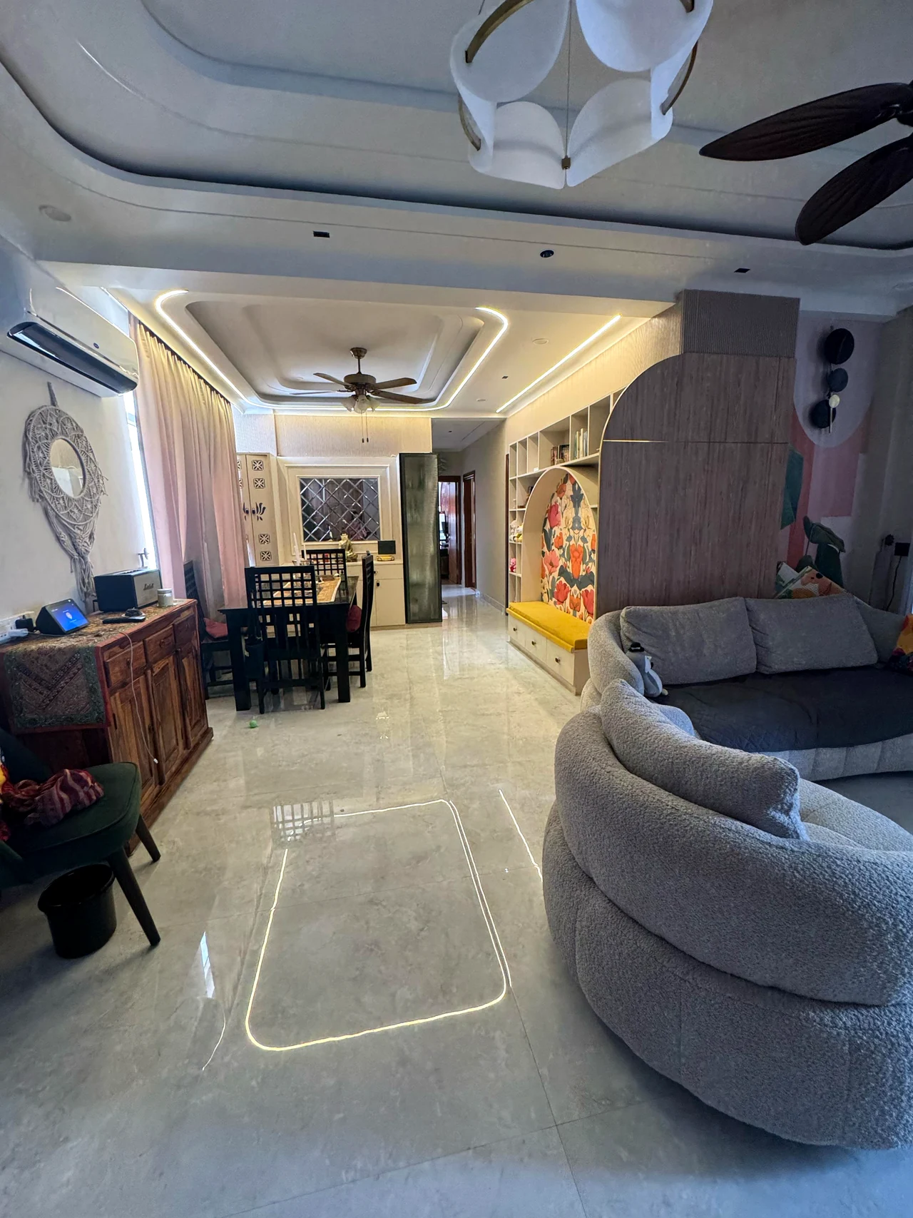 Living room and dining area under a layered ceiling with cove lighting