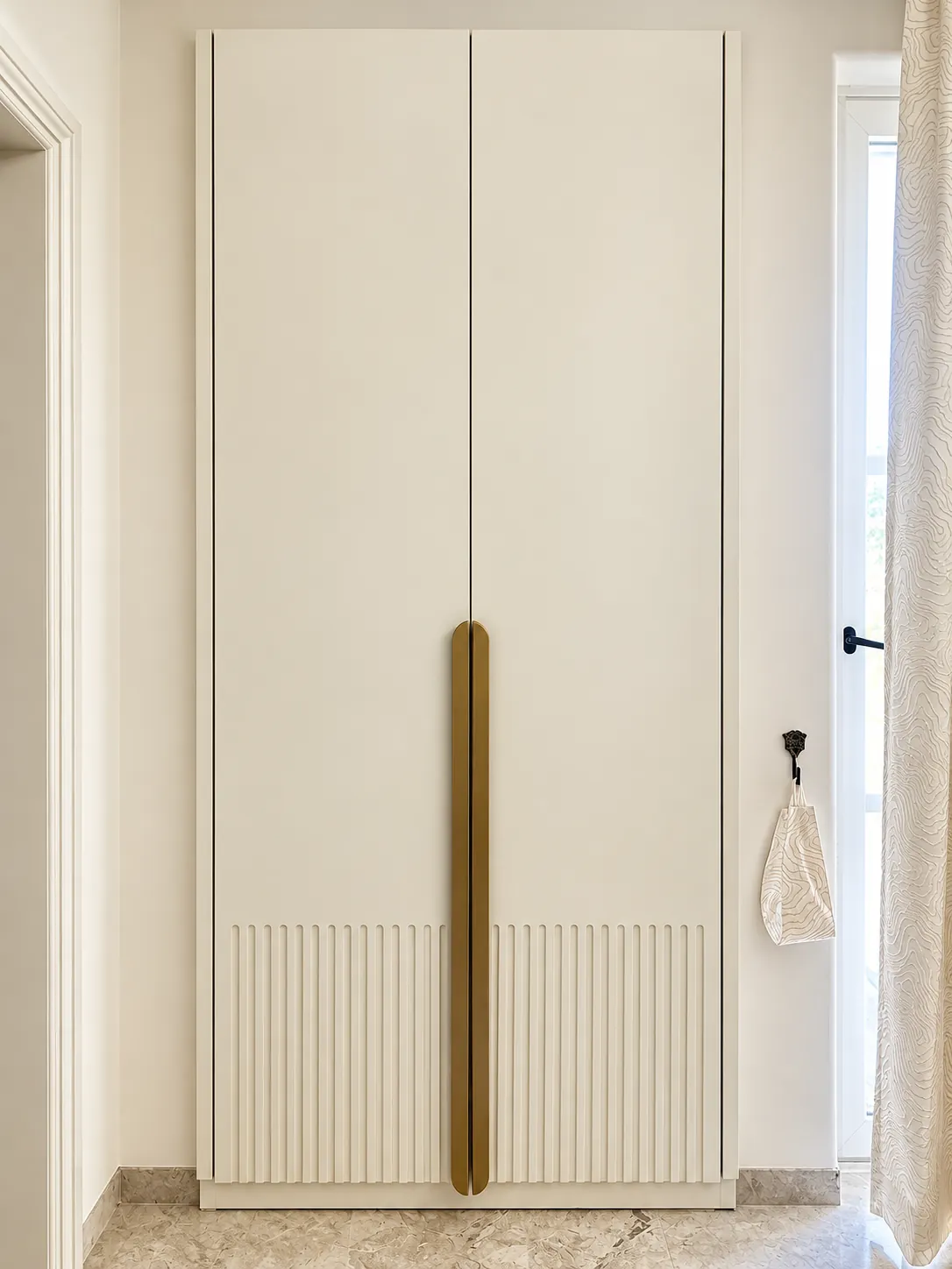 Full-height fluted wardrobe with an elongated brass-tone handle